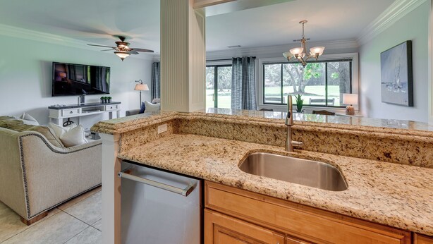 A modern kitchen with granite countertops, a stainless steel sink, and wooden cabinets.
