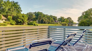 A wooden deck with lounge chairs and a railing overlooking a body of water.