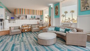 A living room with wicker furniture, a striped rug, and a view of palm trees. - Daytona Beach Studio w/ Ocean View + Amenities! (Daytona Beach)