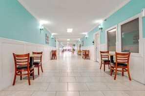 A hallway with wooden chairs and tables, white wainscoting, and teal walls. - Daytona Beach Studio w/ Ocean View + Amenities! (Daytona Beach)