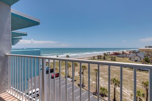 A balcony with a view of the beach, parking area, and buildings. - Daytona Beach Studio w/ Ocean View + Amenities! (Daytona Beach)