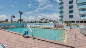 A swimming pool with lounge chairs, a lifeguard stand, and a multi-story building with balconies. - Daytona Beach Studio w/ Ocean View + Amenities! (Daytona Beach)