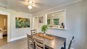 A dining area with a wooden table, four chairs, a ceiling fan, and artwork on the walls. - Quiet Apt: Walk to Daytona Beach + Water Park! (Daytona Beach)