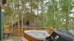 A hot tub on a wooden deck with a wooden fence, a table, and benches. - Hot Tub & Ski Shuttle: Rustic Breckenridge Retreat (Breckenridge)