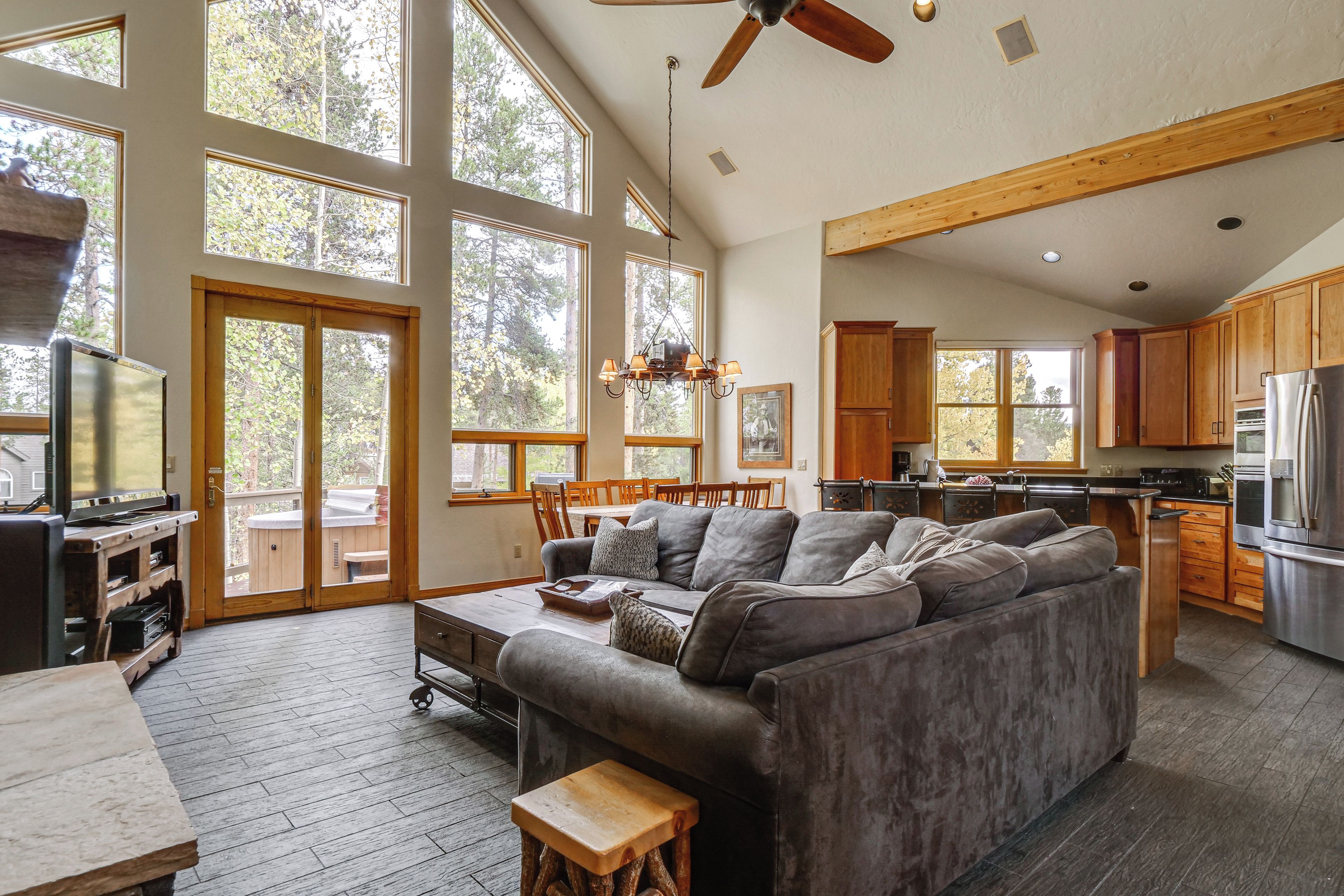 A spacious living area with a large gray sofa, wooden flooring, and a ceiling fan.