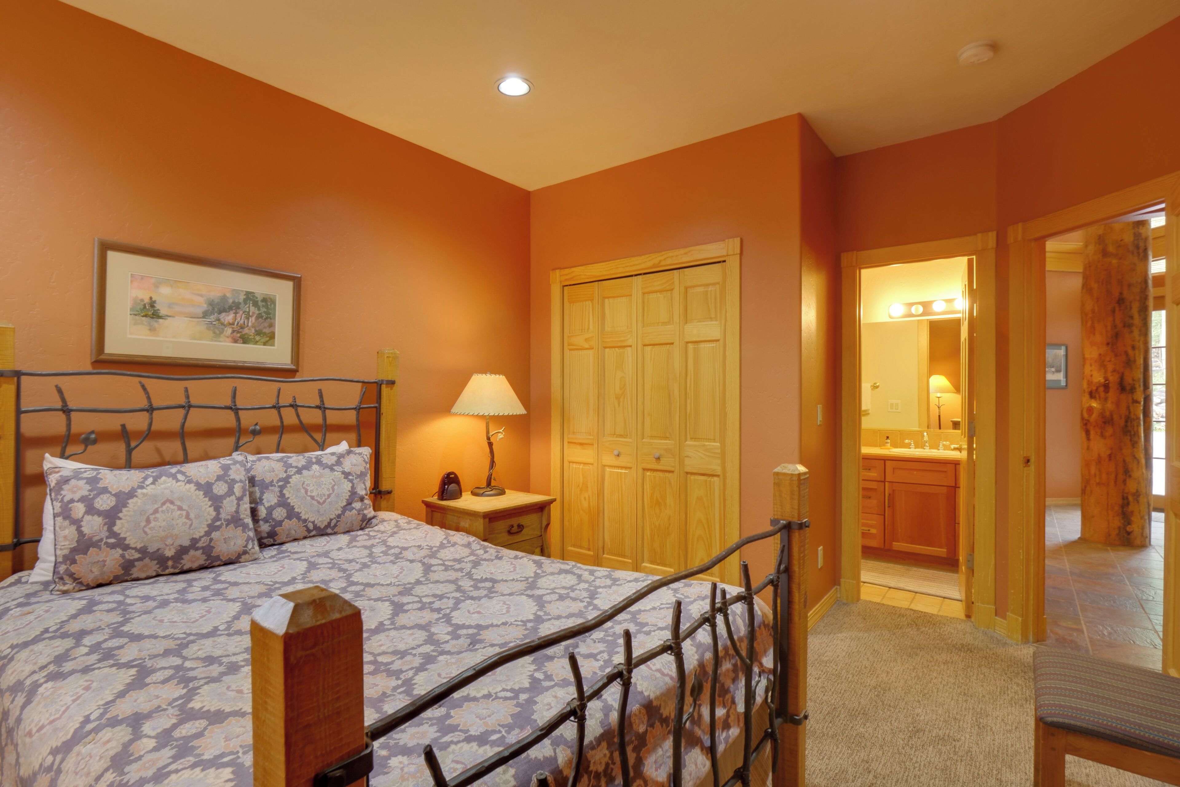 Un dormitorio con cama, mesita de noche, lámpara y un armario de madera.