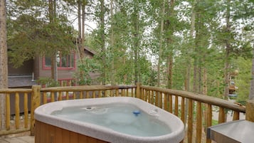 Relax in a hot tub on a raised deck overlooking a forest.