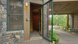 A stone building with a wooden door, a stone wall, and a covered entrance. - Hot Tub & Ski Shuttle: Rustic Breckenridge Retreat (Breckenridge)