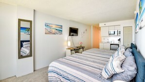 A bedroom with a bed, a desk, a TV, and a kitchenette. - Daytona Beach Vacation Rental w/ Pool Access (Daytona Beach Shores)