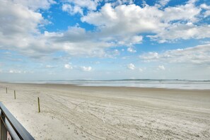 Een strand met een houten omheining en een heldere lucht.