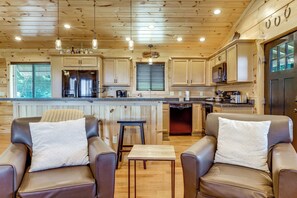 A cabin interior with a kitchen, dining area, and two leather chairs with cushions. - Gorgeous Gatlinburg Cabin: Large Deck & Hot Tub! (Gatlinburg)