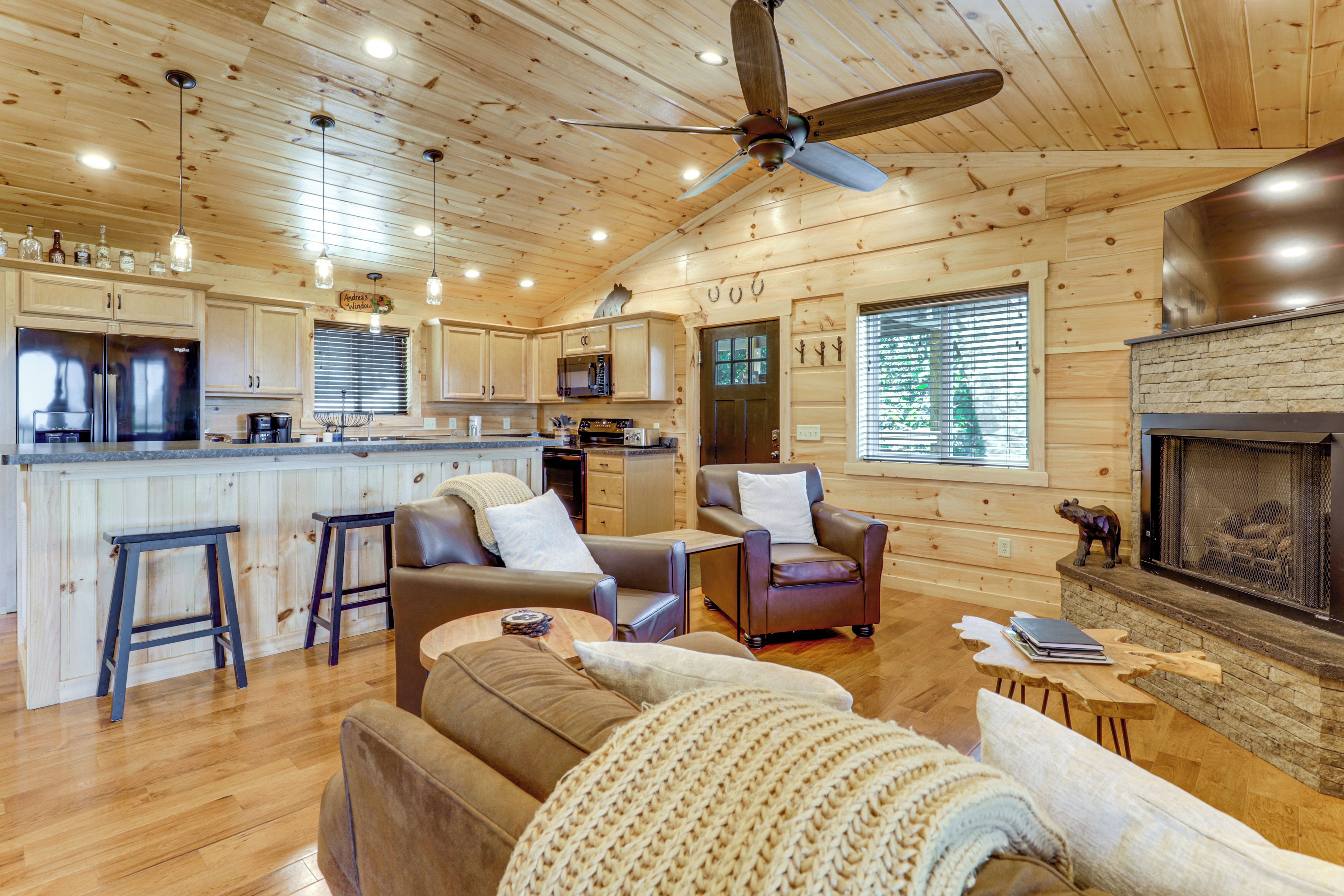 A cabin interior with a kitchen, living area, and fireplace.