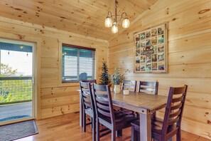 Ein Holzinterieur mit einem Esstisch, Stühlen, einer Chandelüster und einer Wand mit verschiedenen Postern.