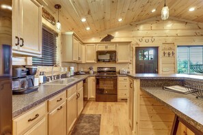 Eine Küche mit Holzschränken, einem Edelstahlkühlschrank, einem Einbauofen und einer Arbeitsplatte aus Granit.