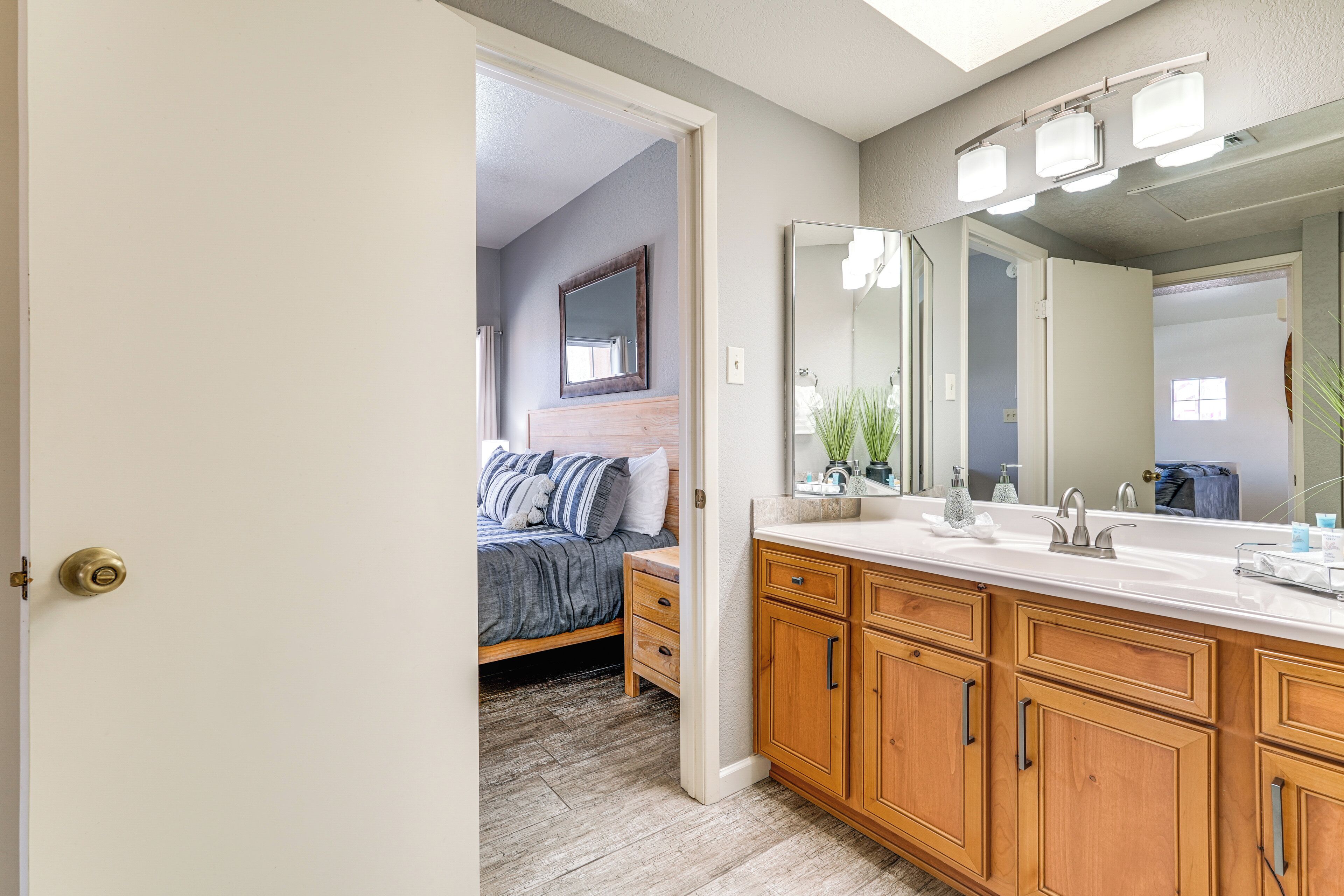 A bathroom with wooden cabinets, a large mirror, and a sink.