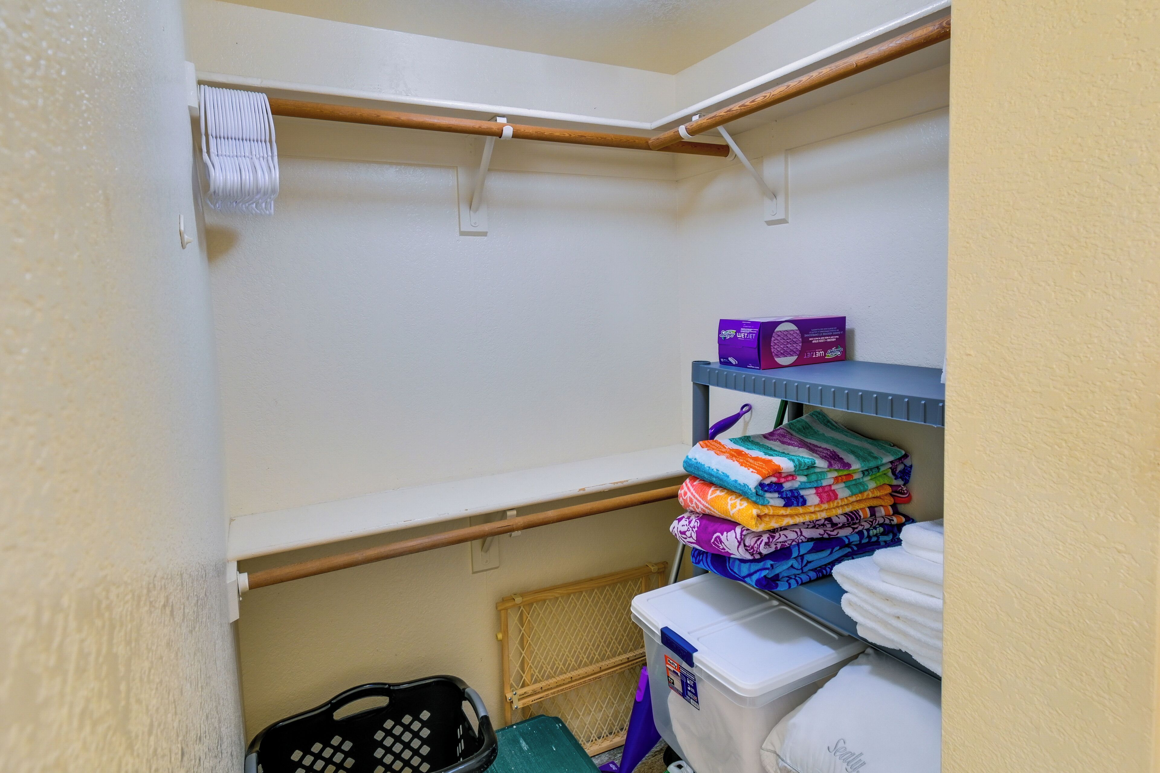 A laundry area with a rack, shelves with folded towels, and a basket.