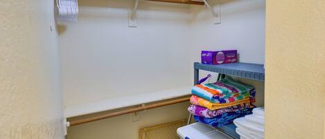 A laundry area with a rack, shelves with folded towels, and a basket.