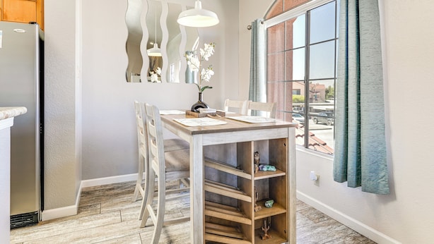 A dining area with a wooden table, chairs, and a vase with flowers. - Walk to Rotary Park: Lake Havasu City Condo (Lake Havasu City)