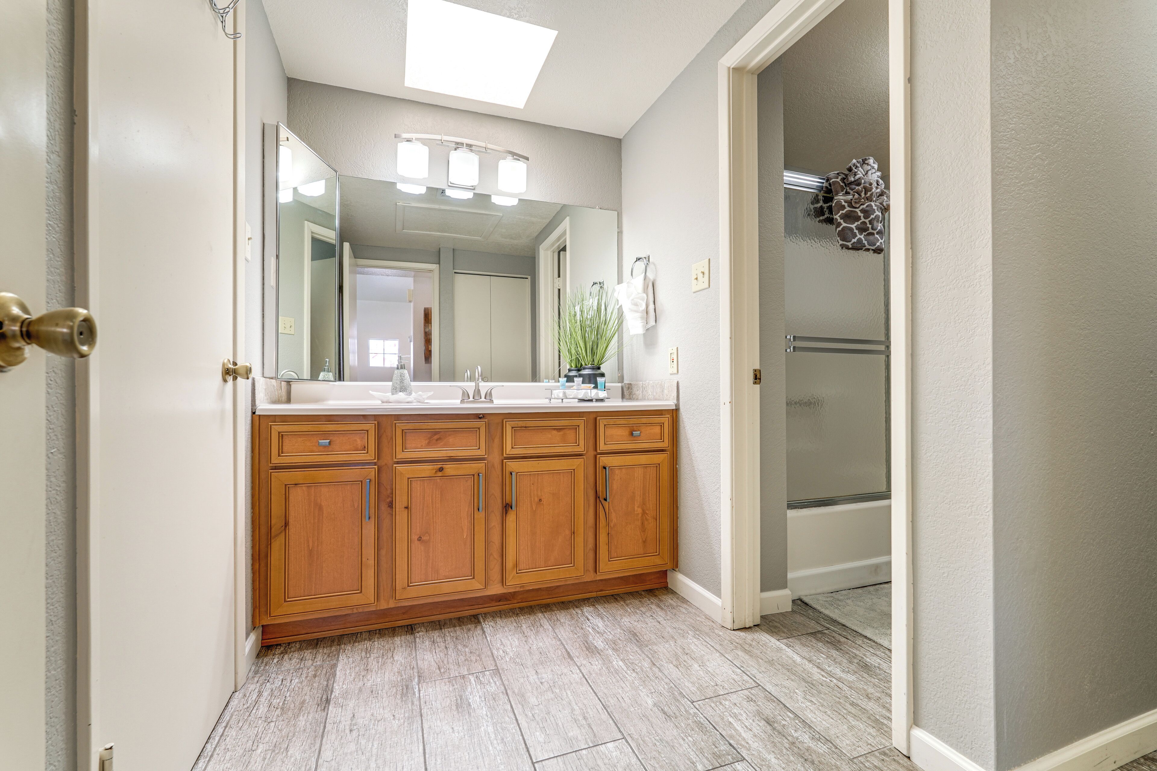A bathroom with a wooden vanity, a large mirror, and a shower area.