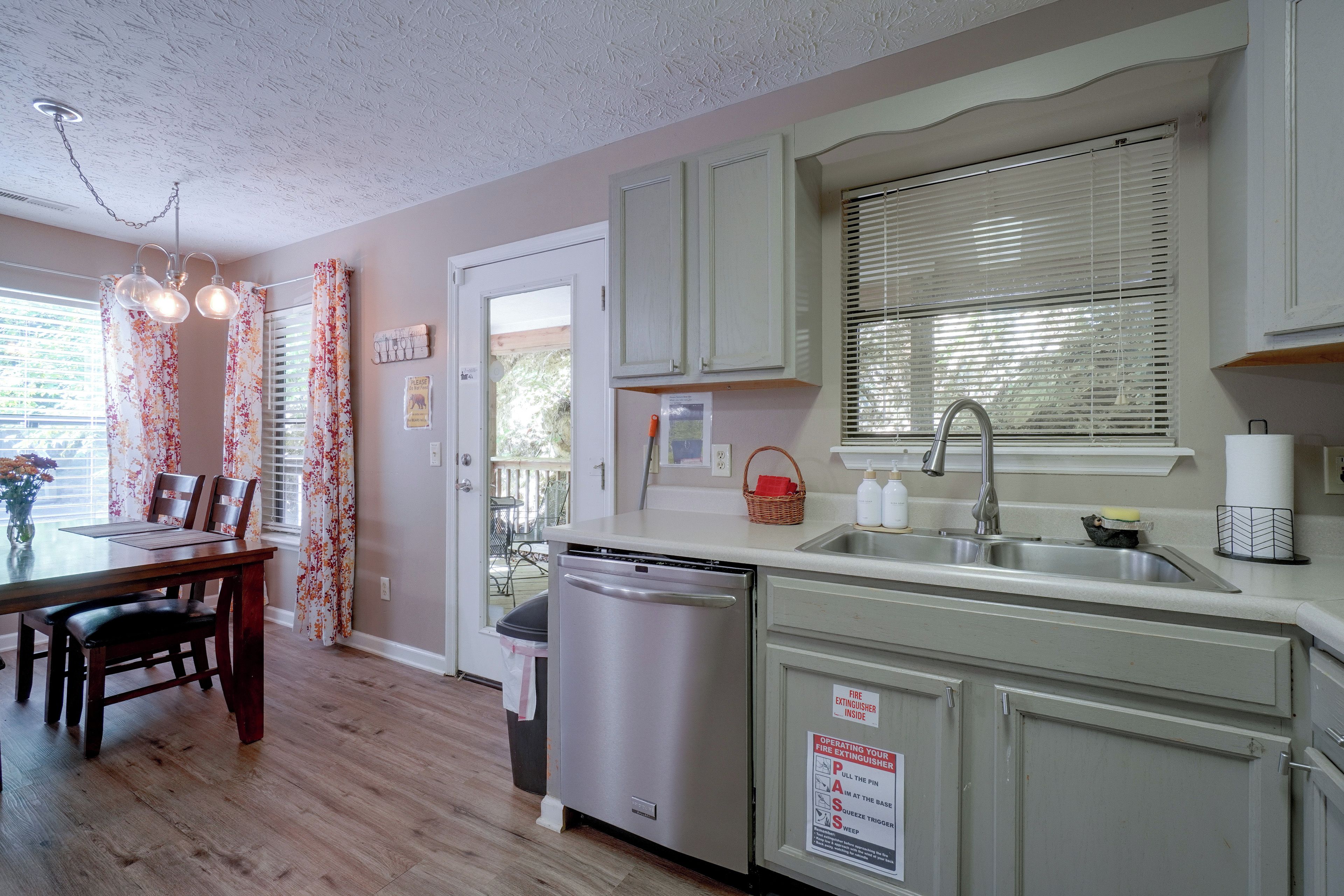 A kitchen with a dishwasher, sink, and a fire extinguisher sign.
