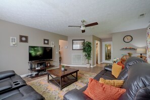 A living room with a television, leather sofas, a coffee table, and a ceiling fan. - Smoky Mtn Cabin w/ Hot Tub Near Ober Gatlinburg (Gatlinburg)