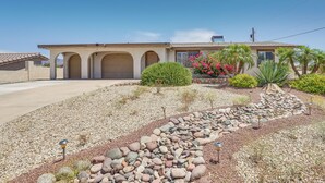 A house with a garage, a landscaped garden with rocks and plants, and a clear blue sky.