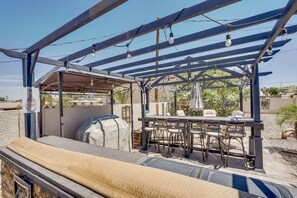 An outdoor patio with a grill, a table with chairs, and a pergola with hanging lights. - Pet-friendly Lake Havasu City Home: 5 Mi to Marina (Lake Havasu City)