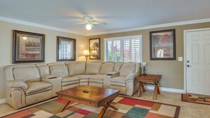 A living room with a sectional sofa, a wooden coffee table, a floor lamp, and framed artwork on the walls.