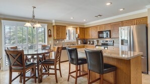 A modern kitchen with wooden cabinets, a stainless steel refrigerator, and a large island with bar stools.