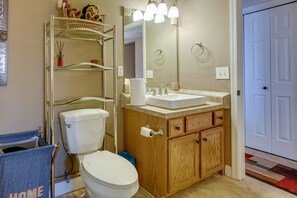 A bathroom with a toilet, sink, wooden cabinets, a mirror, and a towel rack. - Pet-friendly Lake Havasu City Home: 5 Mi to Marina (Lake Havasu City)