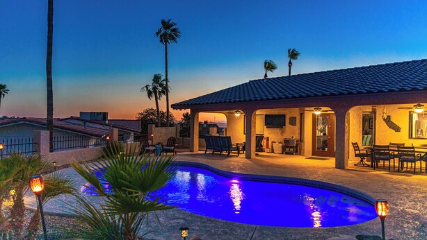 A poolside area with a pool, palm trees, and a building with outdoor seating. - Havasu Oasis w/ Pool & Spa on Quiet Cul-de-sac (Lake Havasu City)