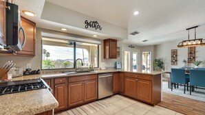 A modern kitchen with wooden cabinets, granite countertops, and a built-in dishwasher. - Havasu Oasis w/ Pool & Spa on Quiet Cul-de-sac (Lake Havasu City)