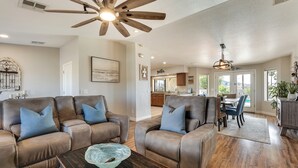 A spacious living room with leather sofas, a wooden coffee table, and a ceiling fan. - Havasu Oasis w/ Pool & Spa on Quiet Cul-de-sac (Lake Havasu City)