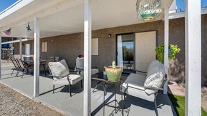 An outdoor patio area with white furniture, a hanging birdcage, and a potted plant.