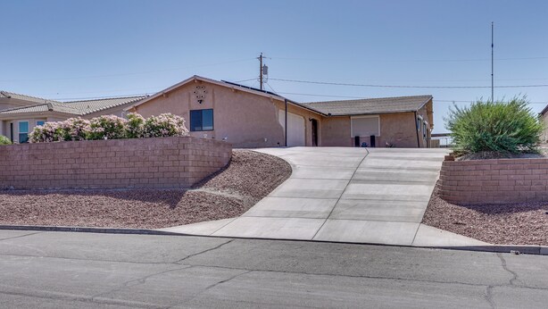 Et hus med indkørsel til garage, en murstensmur og et lille haveområde.