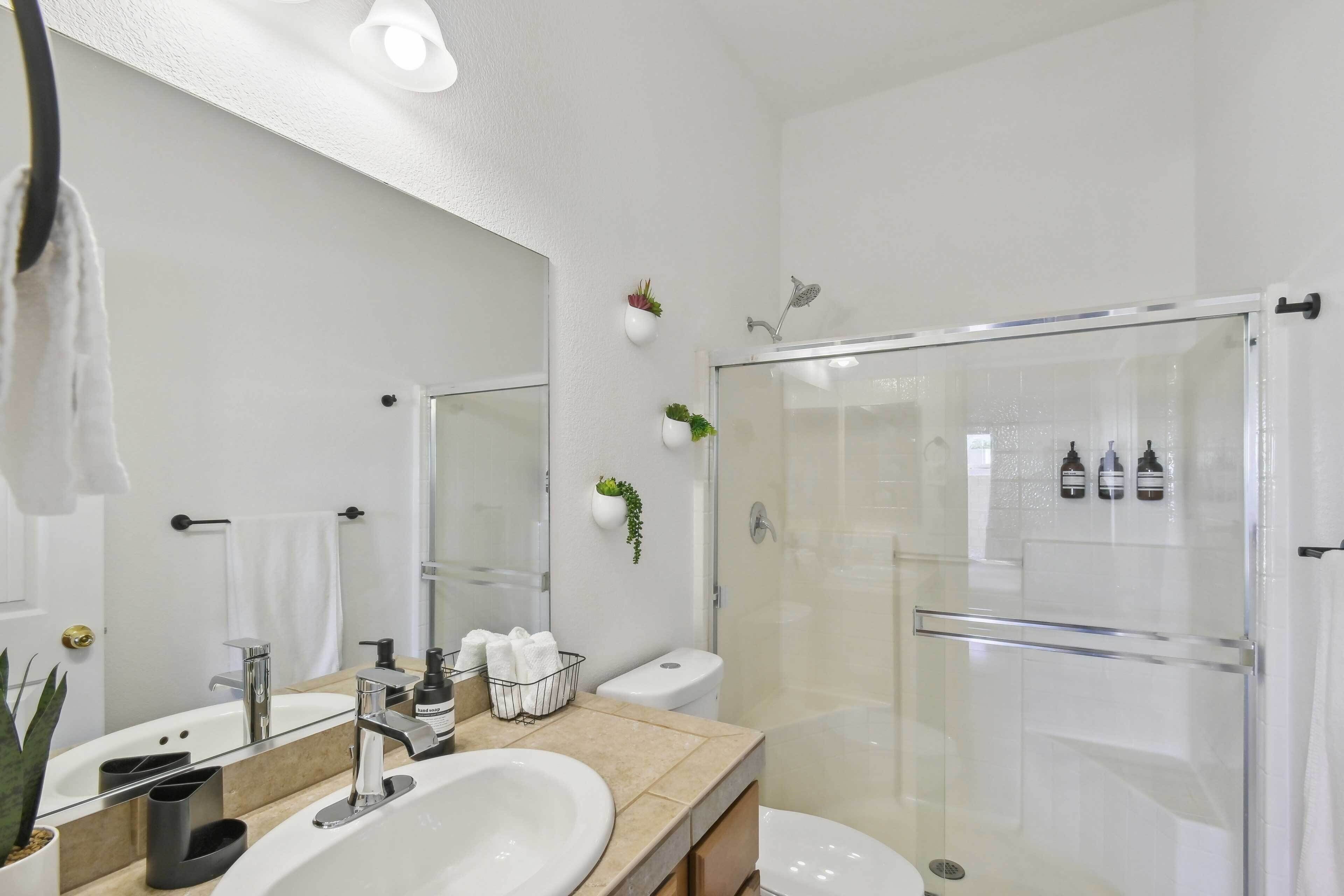 Ein modernes Badezimmer mit großem Spiegel, Waschbecken, Toilette und einer Duschkabine.