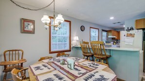 A dining area with a wooden table, chairs, and a chandelier. There is a kitchen area with wooden cabinets and a refrigerator. - Wooded Cabin w/ Pool Table Near Dtwn Gatlinburg! (Gatlinburg)