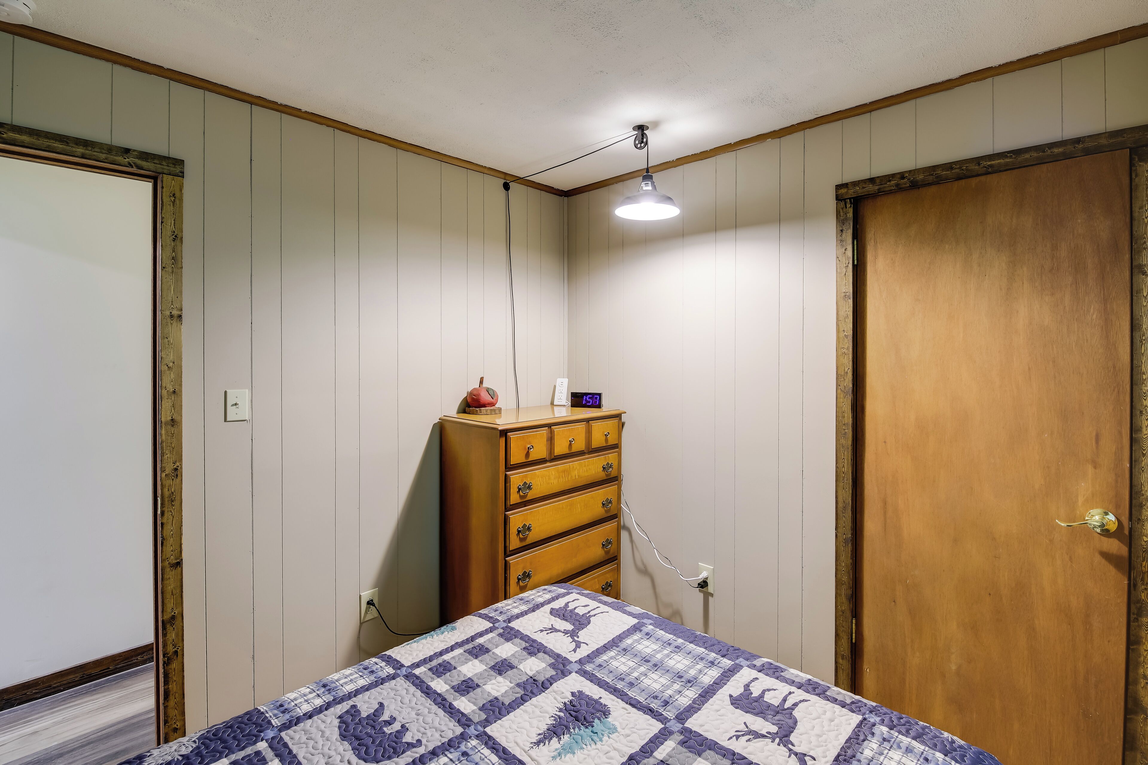 Un dormitorio con cama, cómoda de madera y una puerta.