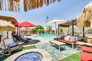 Un jardin avec une piscine, des chaises longues, un jacuzzi et un foyer extérieur.