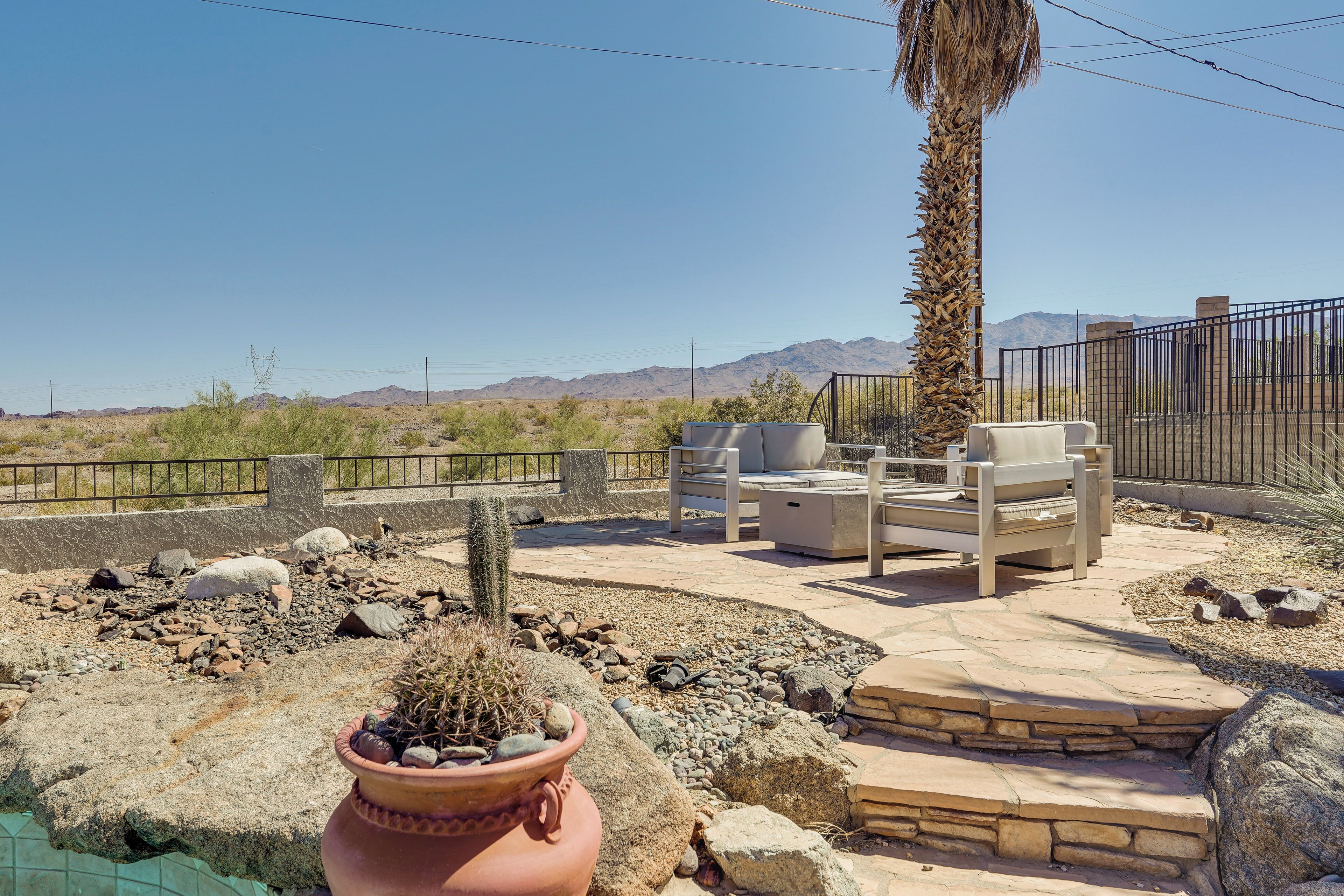 An outdoor patio with seating, a cactus, and a view of mountains.