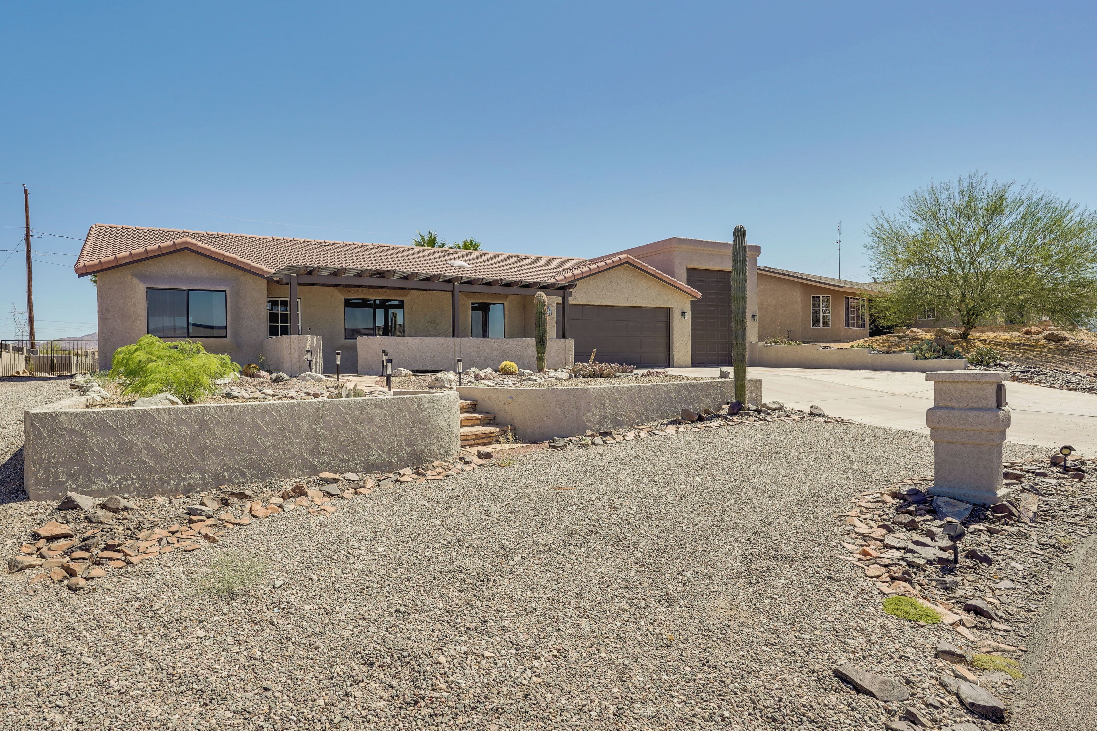 A modern two-story house with a tiled roof, a front garage, and a landscaped front yard with rocks and a cactus.