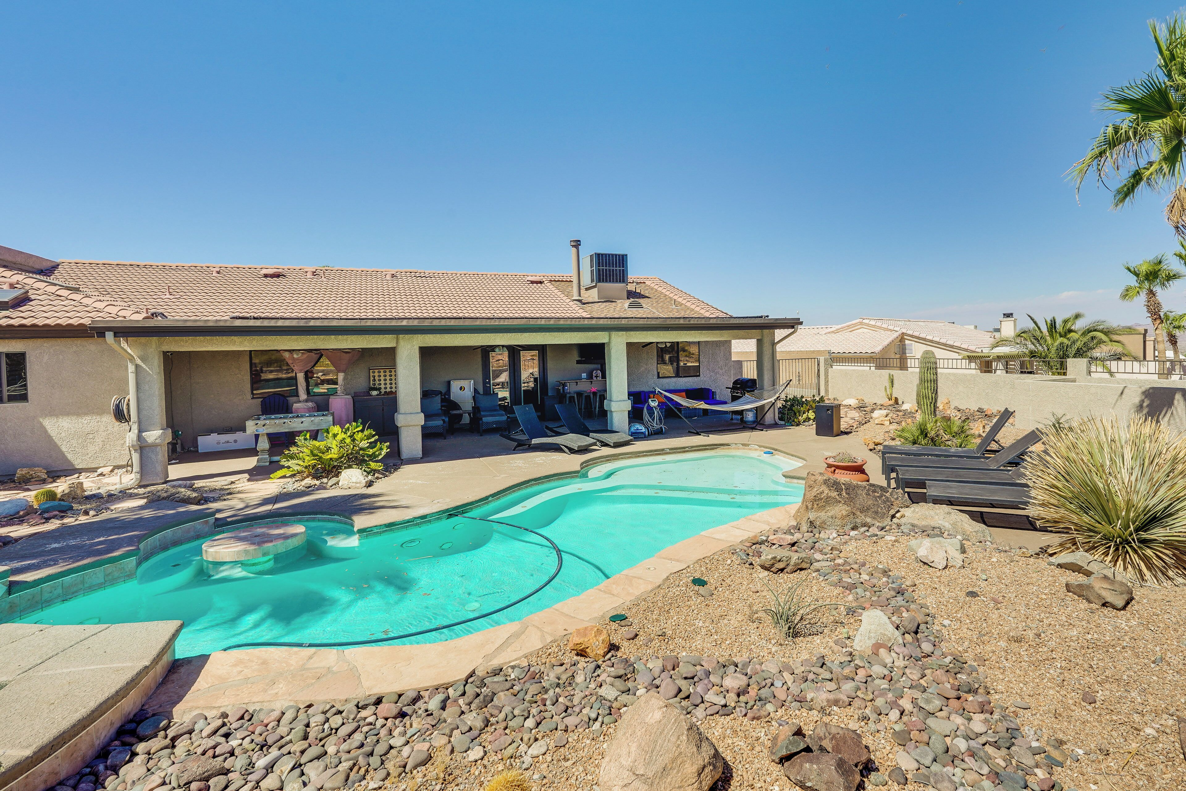 A house with a swimming pool, outdoor seating, and a covered patio.