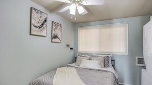 A bedroom with a bed, ceiling fan, artwork, and window blinds. - Washington Vacation Rental Near Seattle & Tacoma (Des Moines)