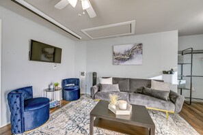 A modern living room with a grey sectional sofa, a blue velvet armchair, and a coffee table. - Washington Vacation Rental Near Seattle & Tacoma (Des Moines)