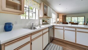 Una cocina moderna con armarios blancos, un lavamanos de acero inoxidable y lavavajillas empotrado.