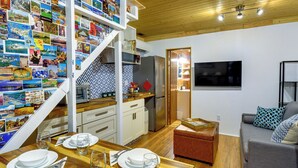 A modern kitchen with a wooden countertop, stainless steel appliances, and a dining area with a wooden table set for four. - Adorable A-frame Cabin, Steps to Lake Cushman! (Hoodsport)