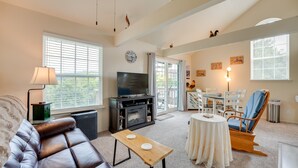 A living room with a leather couch, a wooden coffee table, a TV, and a dining area with a table and chairs. - Branson Vacation Rental w/ Loft ~ 4 Mi to Downtown (Branson)