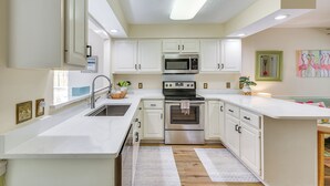 A modern kitchen with white cabinetry, stainless steel appliances, and a central island. - Breezy PCB Vacation Rental w/ Lanai, Walk to Ocean (Panama City Beach)