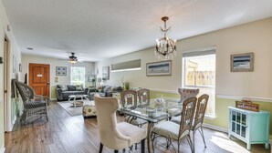 A spacious living room with a glass-top dining table surrounded by wicker chairs, a sofa, and a ceiling fan. - Breezy PCB Vacation Rental w/ Lanai, Walk to Ocean (Panama City Beach)