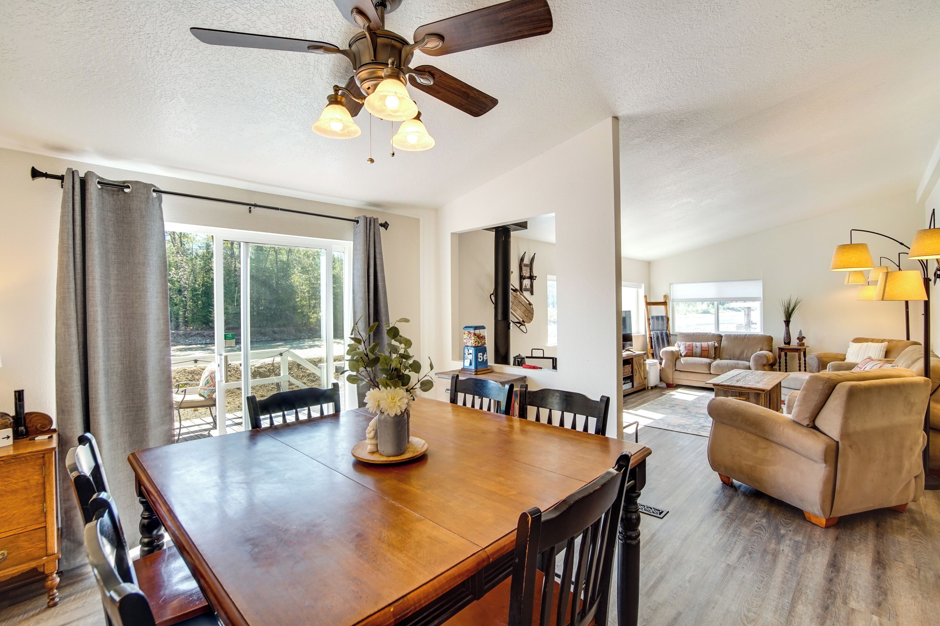 A spacious living room with a wooden dining table, beige sofas, and a ceiling fan.